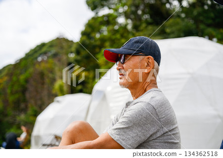 A senior man relaxing in front of a dome tent. [Photo courtesy of Oki Seaside Hotel Miyabi] 134362518