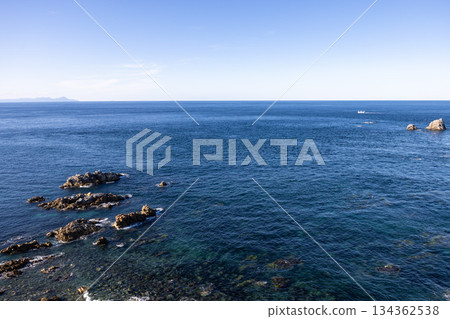 清澈的海水,隱約可見礁石,蔚藍的天空延伸至天際。 清澈的海水,隱約可見礁石,蔚藍的天空延伸至天際。 134362538