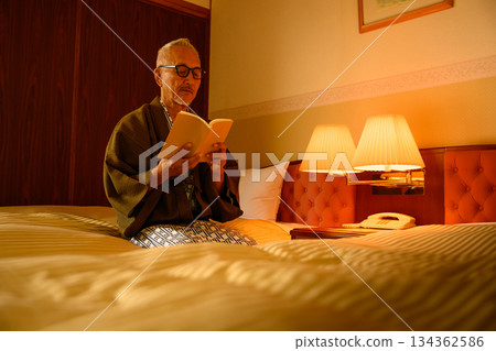 Senior man in traditional Japanese clothing reading at hotel Senior man in traditional Japanese clothing reading at hotel 134362586