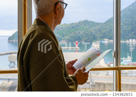 一位老人在窗邊看地圖。 134362651