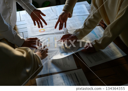 Hands of several people gathered around a document at a meeting Hands of several people gathered around a document at a meeting 134364355