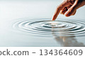 A minimalist concept of ripples spreading when a finger touches the water surface, symbolizing influence and beginnings. 134364609