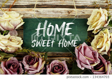 Home Sweet Home text written on wooden plank with flower decoration on wooden background 134364703