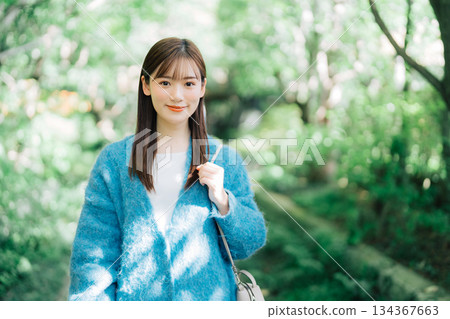A woman walking along a tree-lined avenue of fresh greenery A woman walking along a tree-lined avenue of fresh greenery 134367663