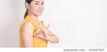 Adult Woman with bandage after received vaccine. Vaccination and Immunization for Influenza, HPV, Zoster, IPD, DTP or Diphtheria, Tetanus and Pertussis, MMR, Hepatitis B, Covid and Varicella vaccine 134367807