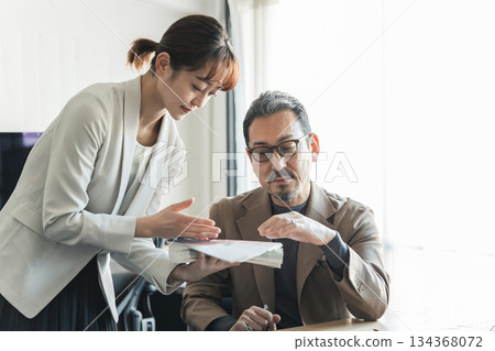 Businessmen having a meeting while looking at documents in the office Businessmen having a meeting while looking at documents in the office 134368072