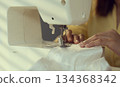Woman clothing designer sews fabrics on a sewing machine. Needlework and handmade hobby. 134368342