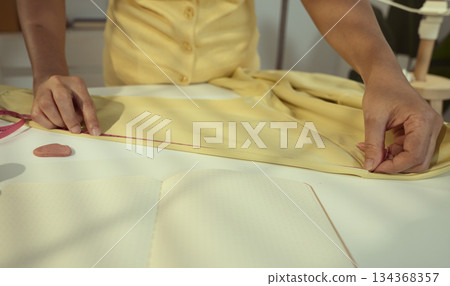 Woman seamstress sleeve length measurement on a shirt using a tape measure by a tailor. 134368357