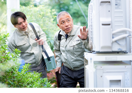 經驗豐富的技術人員和年輕的技術人員正在檢查室外機 經驗豐富的技術人員和年輕的技術人員正在檢查室外機 134368816