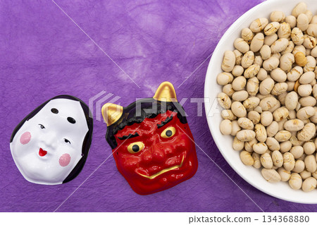 Okame and red demons and a plate of roasted soybeans placed on a purple Japanese paper background Image of the Setsubun (bean throwing) event Okame and red demons and a plate of roasted soybeans placed on a purple Japanese paper background Image of the Setsubun (bean throwing) event 134368880