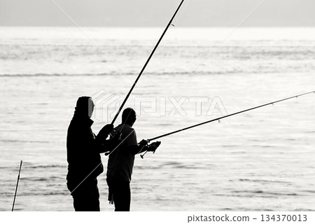 Silhouettes of Bosphorus fishermen in the early morning. A black-and-white, high-contrast image that captures the serene solitude of recreational fishing in Istanbul. Silhouettes of Bosphorus fishermen in the early morning. A black-and-white, high-contrast image that captures the serene solitude of recreational fishing in Istanbul. 134370013