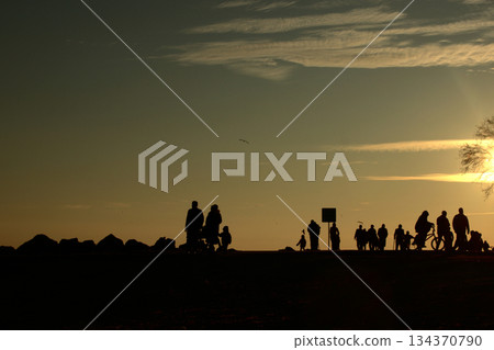 Silhouettes Walking by the Sea at Sunset. Silhouettes Walking by the Sea at Sunset. 134370790