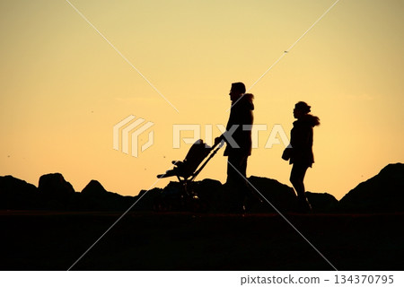 Silhouettes Walking by the Sea at Sunset. Silhouettes Walking by the Sea at Sunset. 134370795