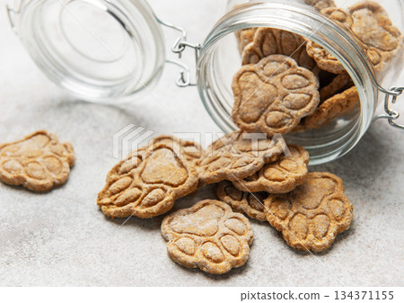 Homemade paw print dog treats spilling from jar Homemade paw print dog treats spilling from jar 134371155