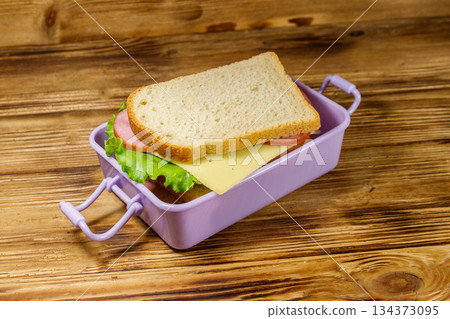 Lunch box with sandwiches on a wooden table Lunch box with sandwiches on a wooden table 134373095