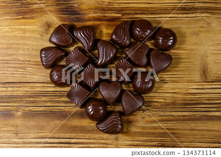Heart shape made of different chocolate candies on wooden table. Top view. Valentine Day concept Heart shape made of different chocolate candies on wooden table. Top view. Valentine Day concept 134373114