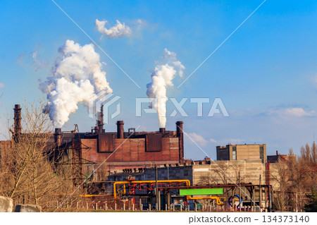 View of old factory with pipes with smoke. Air pollution, environmental damage View of old factory with pipes with smoke. Air pollution, environmental damage 134373140