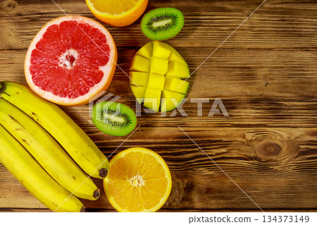 Assortment of tropical fruits on wooden table. Still life with bananas, mango, oranges, avocado, grapefruit and kiwi fruits 134373149