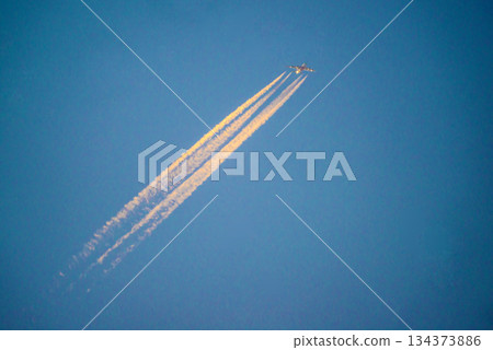 Contrails dyed by the setting sun in the blue sky Contrails dyed by the setting sun in the blue sky 134373886