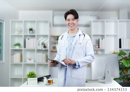 Confident Male Doctor Holding Tablet in Clinic 134374153