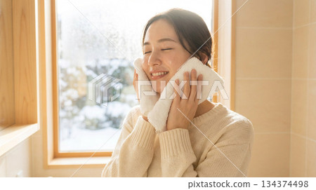 一位二十多歲的日本女性塗抹潤膚露後感覺略微滋潤 | 冬日清晨，略帶拉扯感的護膚品廣告風格 134374498