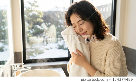 一位二十多歲的日本女性塗抹潤膚露後感覺略微滋潤 | 冬日清晨，略帶拉扯感的護膚品廣告風格 134374499