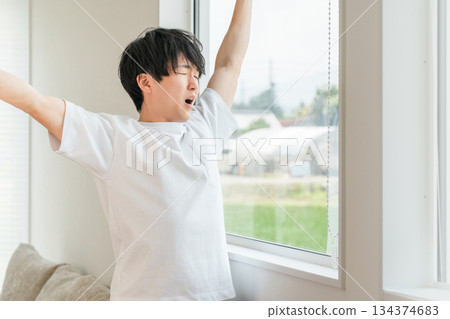 A man basking in the morning sun by the window when he wakes up (deep breathing) 134374683