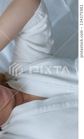 Young woman yawning in bed in morning at home Young woman yawning in bed in morning at home 134375981