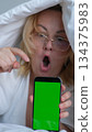 green screen for chroma key advertising Shocked lady staring at smartphone with open mouth. Middle-aged woman reading surprising message on phone, amazing news at night 134375983