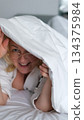 Playful cozy bed face happy woman laughing smiling rejoice flirt girl looking duvet peek toothy dental smile bedroom home pleasure tenant glad enjoying joy bed positive dentistry delight homeowner 134375984