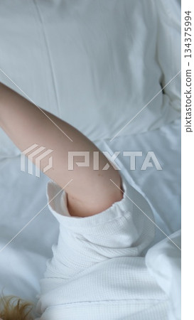 Cheerful adult woman taking selfie with phone while resting on bed in the morning. Happy millennial female sharing self portrait on social media network. 134375994
