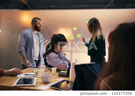 Coworkers brainstorming startup ideas with sticky notes in modern office. 134377209