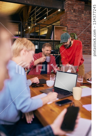 Team reviewing content together in relaxed coworking environment. 134377245