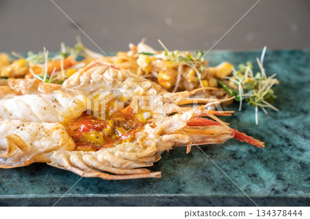 Close up to the Lobster Pad Thai is ready to serve with fried noodle, tofu and other ingredients on a rectangular plate in studio light. Close up to the Lobster Pad Thai is ready to serve with fried noodle, tofu and other ingredients on a rectangular plate in studio light. 134378444