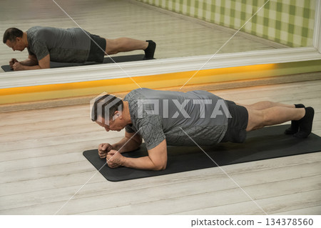 Senior Man holding plank pose during yoga workout. Stretching, Balance and Flexibility Training Senior Man holding plank pose during yoga workout. Stretching, Balance and Flexibility Training 134378560