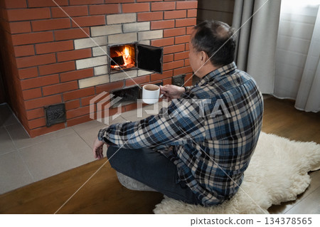 Relaxing by fireplace with hot drink at home 134378565