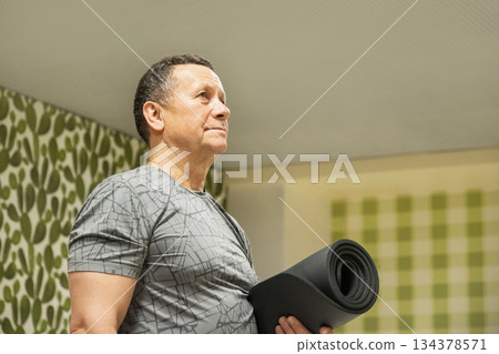 Adult man holding yoga mat before training. Senior Man Yoga. Stretching, Balance and Flexibility Training 134378571