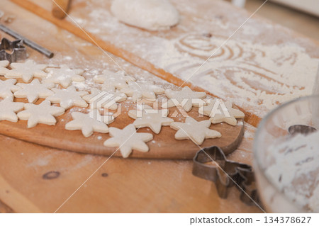 Star shaped raw cookies ready to bake. Baking sheet uncooked biscuits homemade cakes and ingredients on kitchen table. Homemade food preparing process. Household housewife housework concept 134378627