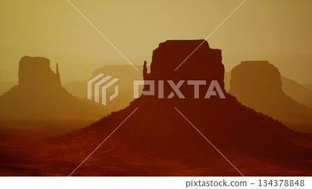 Silhouettes of unique rock formations stand tall against a stunning desert sunset. The warm golden light casts dramatic shadows, creating a serene atmosphere of natural beauty. Silhouettes of unique rock formations stand tall against a stunning desert sunset. The warm golden light casts dramatic shadows, creating a serene atmosphere of natural beauty. 134378848