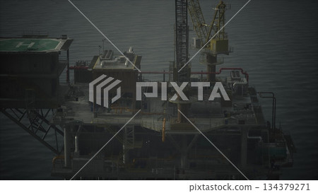 An offshore oil platform rises majestically from dark waters, with a yellow crane reaching towards the sky. The scene captures the blend of industry and nature during a serene twilight moment. 134379271