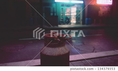 A rustic container rests on a quiet street, illuminated by soft neon lights reflecting off wet pavement. The calm scene invites contemplation amid the citys vibrant nightlife. A rustic container rests on a quiet street, illuminated by soft neon lights reflecting off wet pavement. The calm scene invites contemplation amid the citys vibrant nightlife. 134379353
