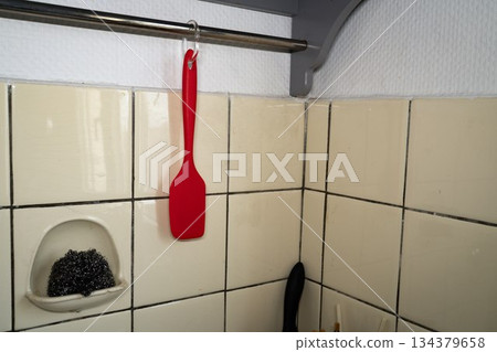 Red scrapink spatula hanging over the sink space 134379658