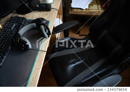 gamer headphones on a table with PC and old gamer chair 134379659