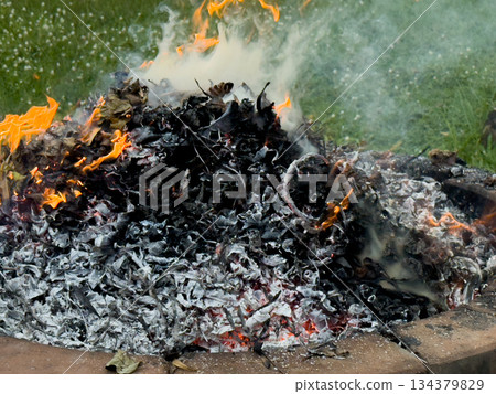 dangerously hot orange and red flames with dense black smoke consuming wood and embers 134379829