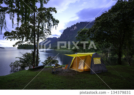 Camping tent on green grass in the morning, antique gas lamps, retro chairs, with outdoor coffee-making facilities on tables in a forest camping area. 134379831