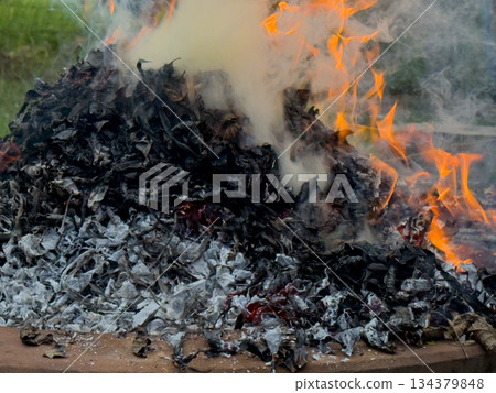 dangerously hot orange and red flames with dense black smoke consuming wood and embers 134379848