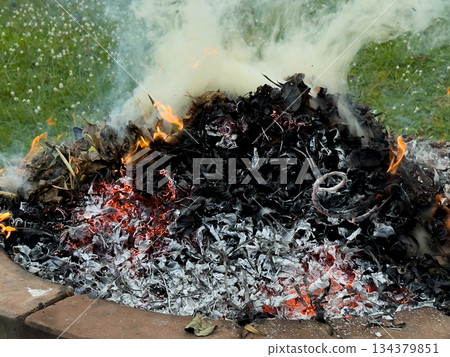 dangerously hot orange and red flames with dense black smoke consuming wood and embers 134379851