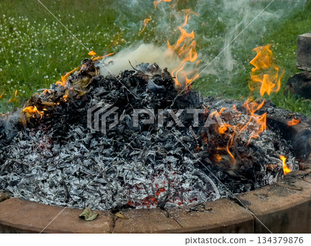 dangerously hot orange and red flames with dense black smoke consuming wood and embers dangerously hot orange and red flames with dense black smoke consuming wood and embers 134379876