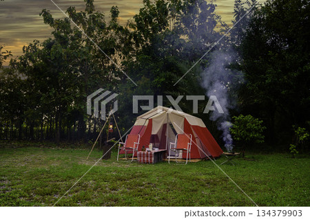 Camping tents at night, vintage cabin tents, antique oil lamps, retro chairs, and a group of camping tents with outdoor coffee-making facilities on wooden tables in a forest camping area. Camping tents at night, vintage cabin tents, antique oil lamps, retro chairs, and a group of camping tents with outdoor coffee-making facilities on wooden tables in a forest camping area. 134379903