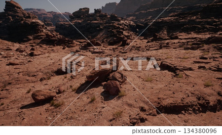 Breathtaking desert scene features striking rock formations under a bright sky. Sunlight casts shadows on the rough terrain, showcasing natures beauty and rugged textures in the wild. 134380096